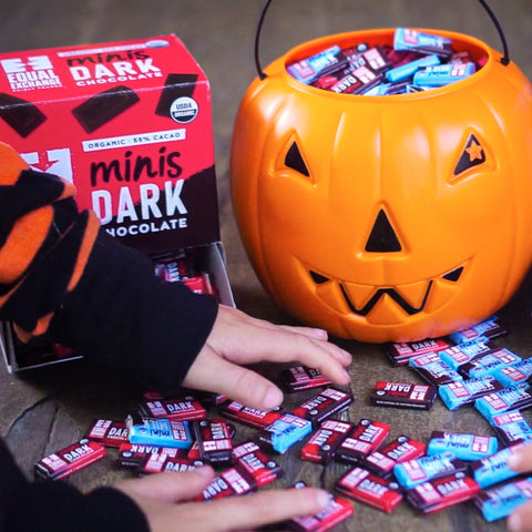 Kids hands grabbing milk and dark chocolate minis with pumpkin pail and box of dark minis in the background