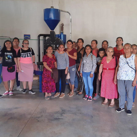 Group of women posing in front of a coffee roasting machine.