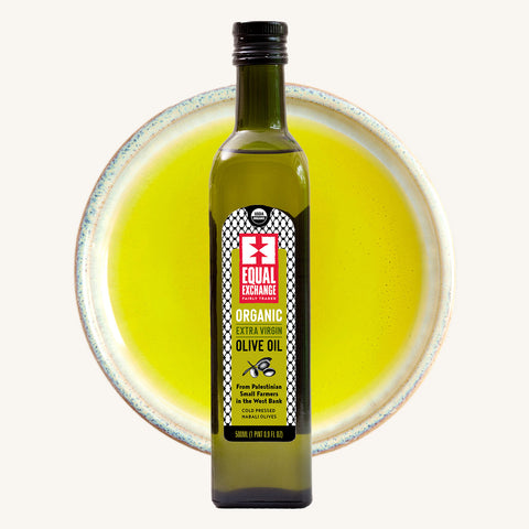 Bottle of Equal Exchange Olive Oil over a bowl of olive oil in background