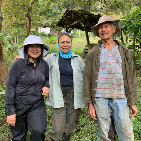 Anna standing with Martha and her brother Jaime with his lush, diverse farm in the background