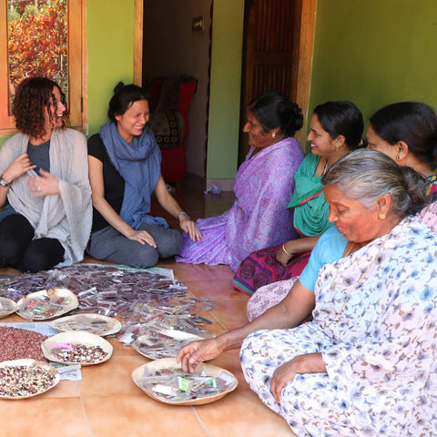 Group of women sitting around a table with heirloom seeds on it, in a community setting.