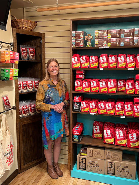 Linda Elliott standing in front of her display shelves filled with Equal Exchange coffee bags