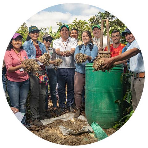 group of farmers and Equal Exchange staff holding organic material for composting