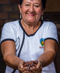 cacao farmer from ACOPAGRO co-op in Peru smiling and holding a handful of cocoa beans