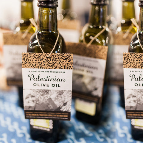 Palestinian Olive Oil tags hanging from bottles at a table sale