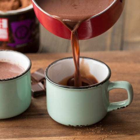 dark hot chocolate being poured from a pot into a mug ready to drink