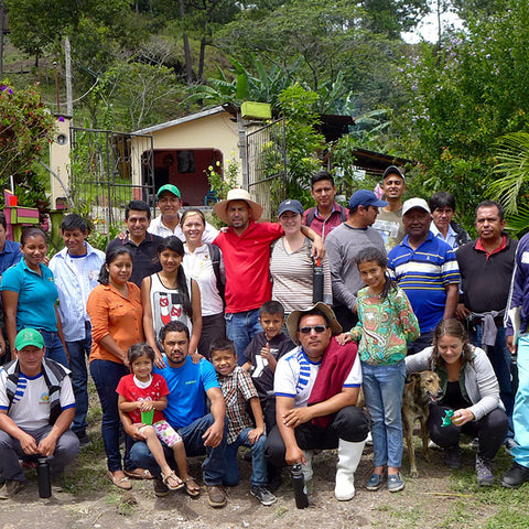 large group of people in a rural jungle setting smiling at the camera