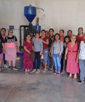 Group of women posing in front of a coffee roasting machine.