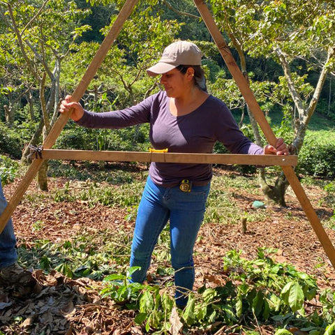Marina Elizabeth De León Tzunún holding a wooden A frame structure on her farm in Guatemala