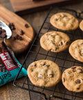 Rack of chocolate chip cookie cooling with a bag of Equal Exchange chocolate chips in the background