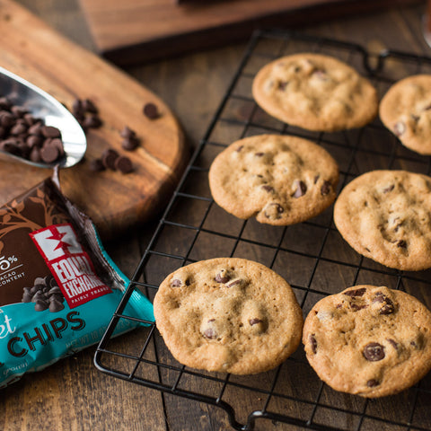 Rack of chocolate chip cookie cooling with a bag of Equal Exchange chocolate chips in the background