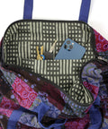 A bag with a colorful, patterned interior is open, revealing three keys on a keychain and a blue smartphone inside. The bag has blue handles and a zippered opening.