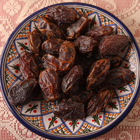 close up of dried medjool dates placed on a colorful plate with a lace tablecloth in the background