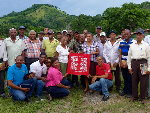 group of CONACADO co-op members holding a red Equal Exchange banner in front of green hillside in the Domincan Republic