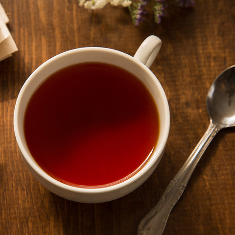 Cup of brewed Organic Black Tea sitting on a table with spoon