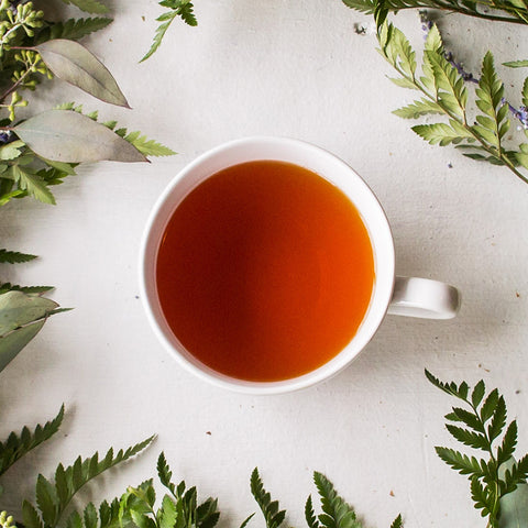 cup of brewed Organic Decaf English Breakfast tea surrounded by floral arrangement