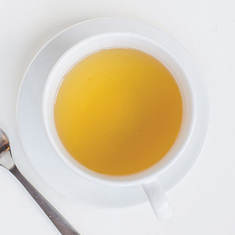 cup of green tea with ginger next to a spoon