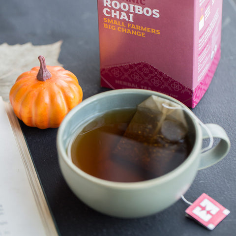 cup of rooibos chai tea brewing with box in background