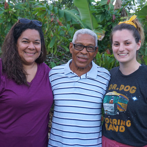 Two Equal Exchange employees, Jackie Rhone and Megan Chisholm, standing next to Noberto Frias, a cacao farmer and member of CONACADO co-op in the Dominican Republic