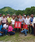 Group of CONACADO members together in front of their cacao farm holding an Equal Exchange bandana