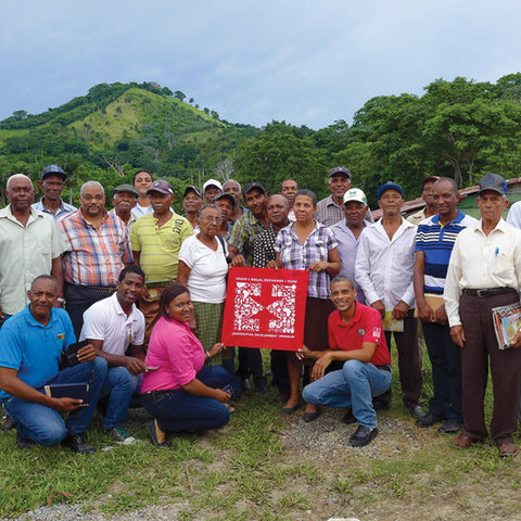 Group of CONACADO members together in front of their cacao farm holding an Equal Exchange bandana