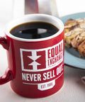 Mug of black coffee with Equal Exchange logo and text, "Never Sell Out"