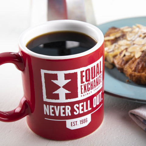 Mug of black coffee with Equal Exchange logo and text, "Never Sell Out"