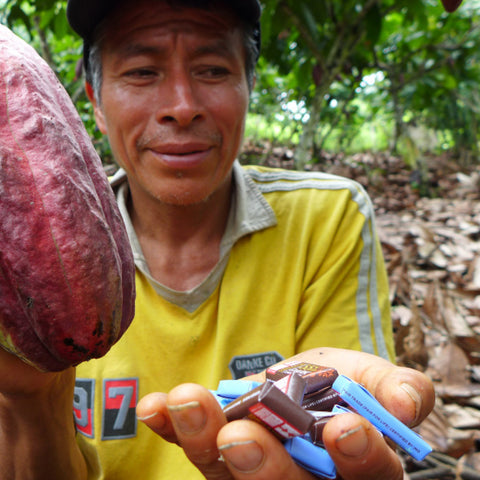 Peruvian cacao farmer holding a cacao pod and Equal Exchange minis in the other hand